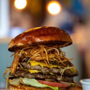 a large hamburger sitting on top of a wooden cutting board