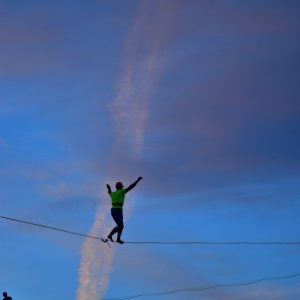 man wearing green crew-neck shirt walking on rope